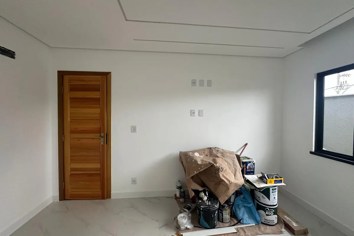 Quarto vazio antes do projeto, com paredes brancas e material de obra