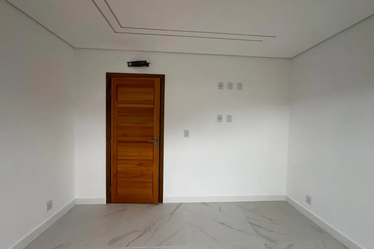 Quarto vazio antes do projeto, com porta de madeira e piso porcelanato